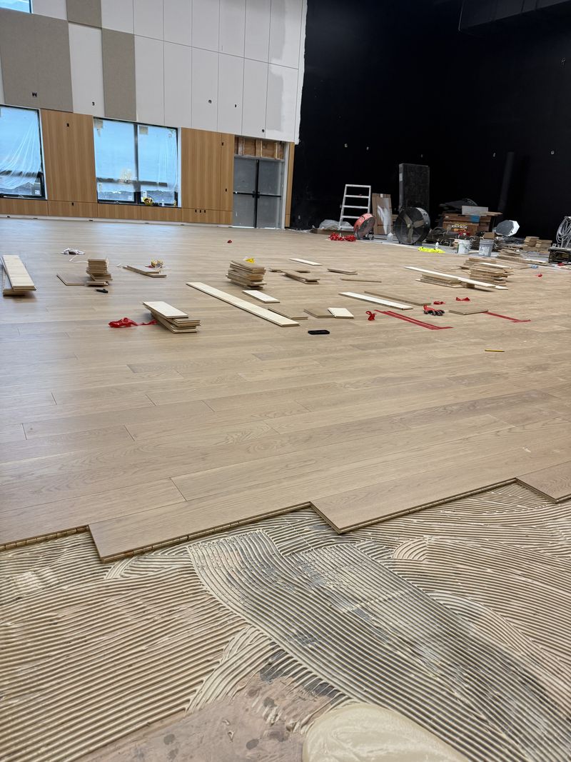 Notched-trowel adhesive spread ahead of the glue-down hardwood, Pemberton
